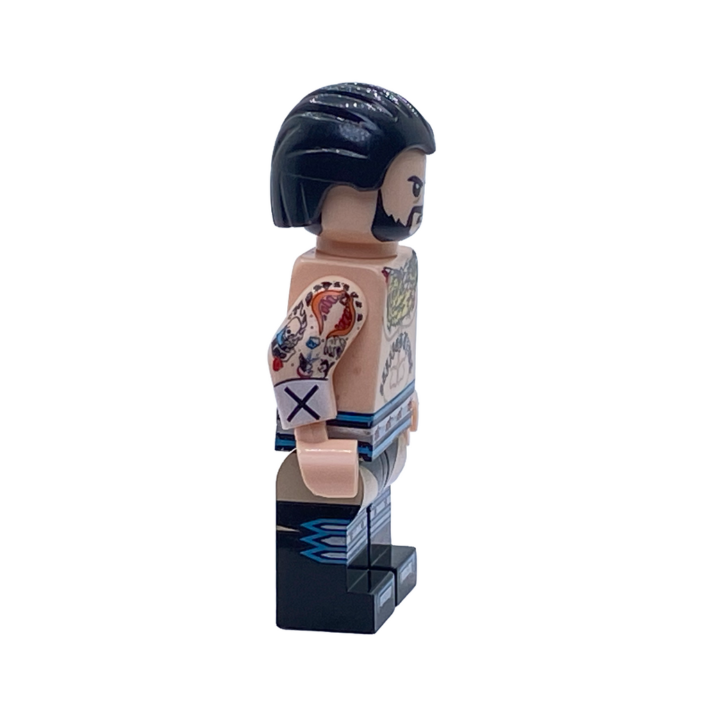 Side profile of the CM Punk WWE custom minifigure showing black hair, beard, arm tattoos and blue-and-white wrestling gear.